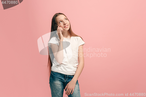 Image of The happy teen girl standing and smiling against pink background.