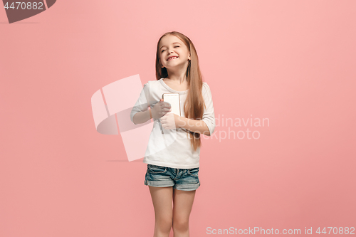 Image of The happy teen girl standing and smiling against pink background.