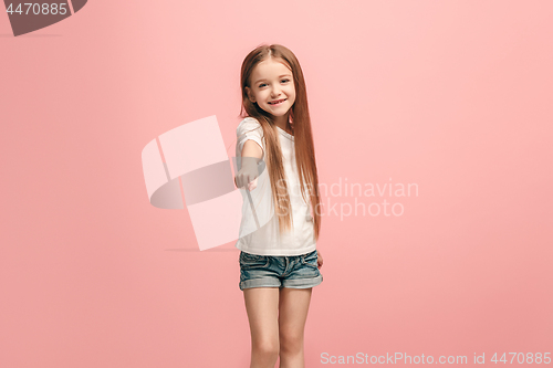 Image of The happy teen girl pointing to you, half length closeup portrait on pink background.