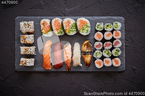 Image of Sushi rolls set with salmon and tuna fish served on black stone board