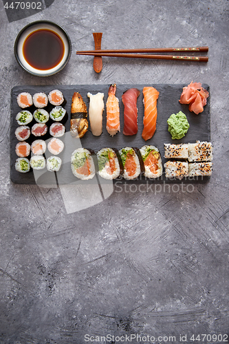 Image of Composition of different kinds of sushi rolls placed on black stone board
