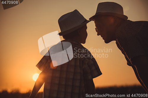 Image of Father and son playing in the park at the sunset time.