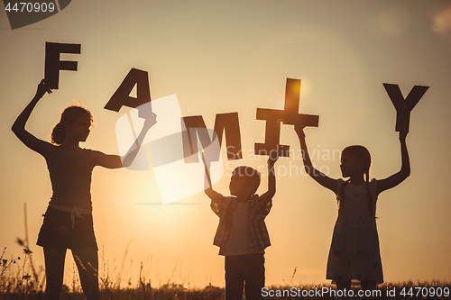 Image of Happy children standing on the field at the sunset time.