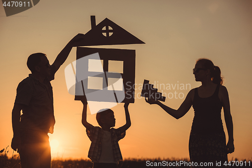 Image of Happy family standing on the field at the sunset time.