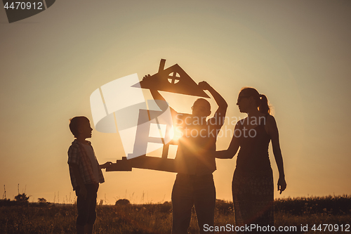 Image of Happy family standing on the field at the sunset time.