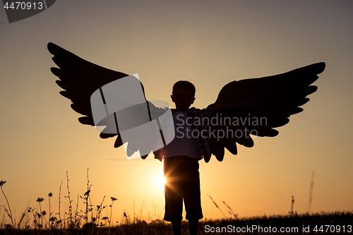 Image of Little boy playing with cardboard toy wings in the park at the s