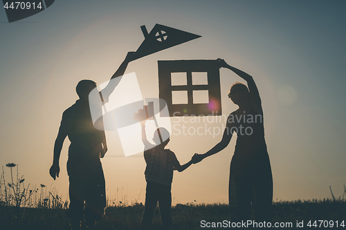 Image of Happy family standing on the field at the sunset time.