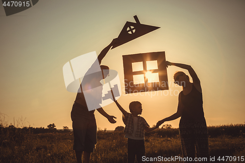 Image of Happy family standing on the field at the sunset time.