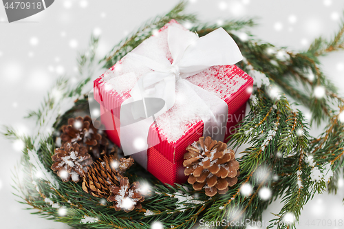 Image of christmas gift and fir wreath with cones on snow