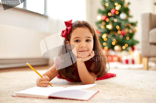 Image of little girl writing christmas wish list at home