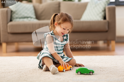 Image of happy baby girl playing with toy car at home