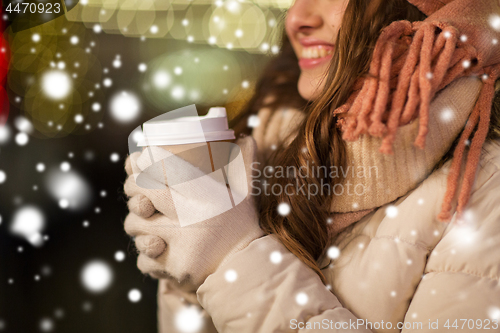 Image of happy woman with coffee over christmas lights