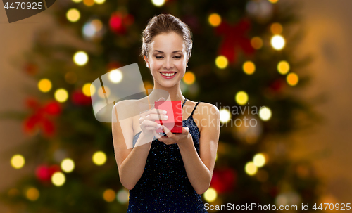 Image of woman with red gift box over christmas tree lights