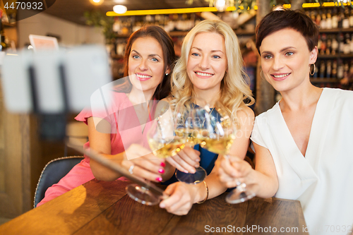 Image of women taking picture by selfie stick at wine bar