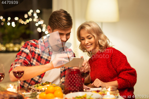 Image of couple with smartphone at home christmas dinner