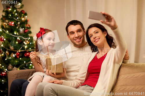 Image of happy family with christmas present at home