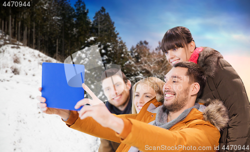 Image of happy friends taking selfie by tablet pc in winter