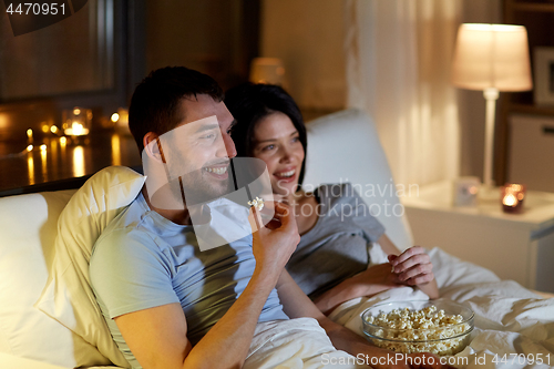 Image of couple with popcorn watching tv at night at home