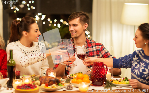 Image of happy friends drinking red wine at christmas party