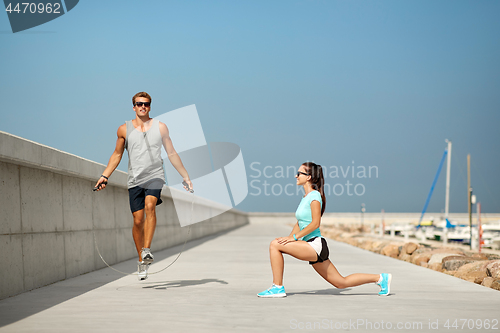 Image of happy couple warming up on pier before training