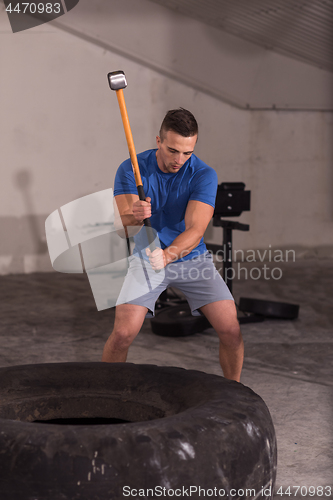 Image of man workout with hammer and tractor tire