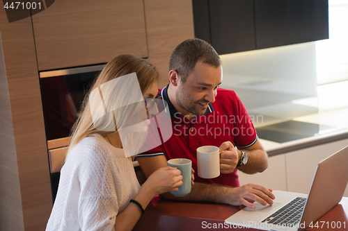 Image of couple drinking coffee and using laptop at home