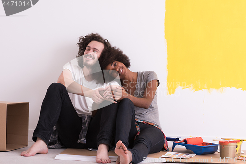 Image of young multiethnic couple relaxing after painting