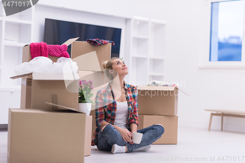 Image of woman with many cardboard boxes sitting on floor