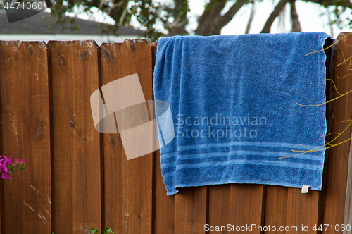 Image of Blue beach towel hanging on fence