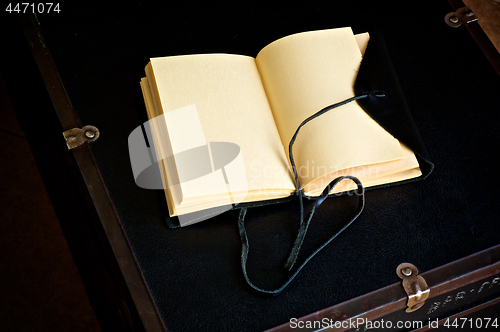 Image of blank open leather bound journal on old trunk
