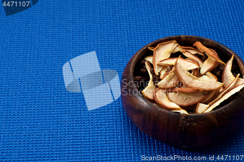 Image of wooden bowl with dried apple blue background