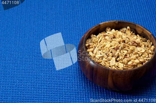 Image of wooden bowl with granola blue background