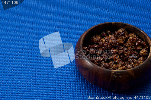 Image of wooden bowl with homemade raisins blue background