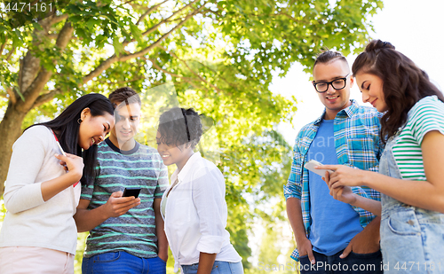 Image of happy friends with smartphones at summer park
