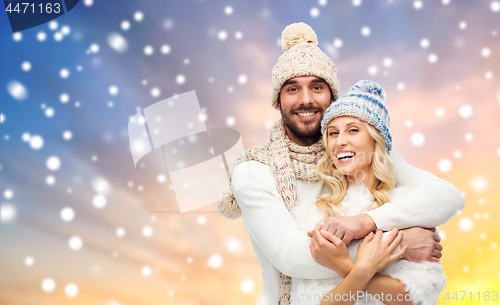 Image of happy couple in winter clothes hugging over snow