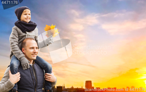 Image of father carrying son with autumn leaves in city