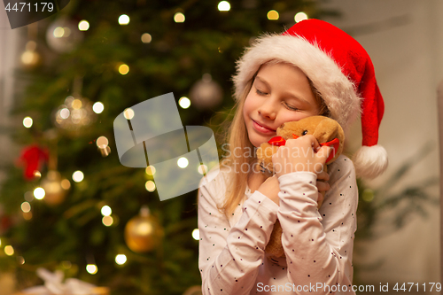 Image of smiling girl in santa hat with christmas gift