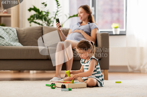 Image of happy baby girl playing with toy blocks at home
