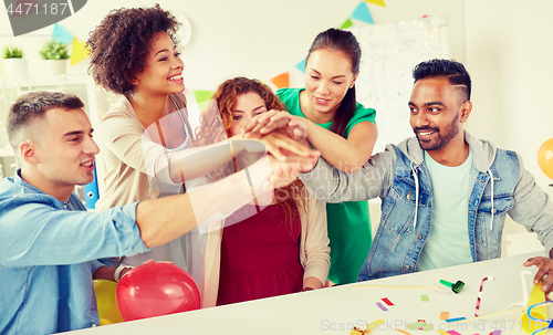 Image of happy business team at office party holding hands