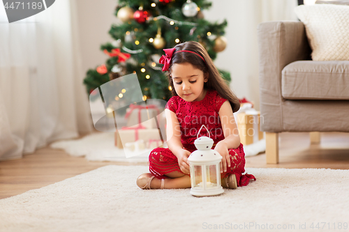 Image of little girl with lantern at home on christmas