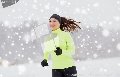 Image of happy woman running along snow covered winter road