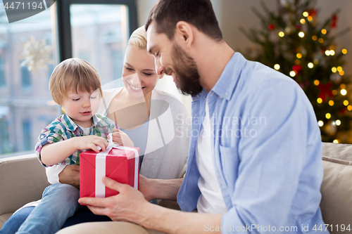 Image of happy family with christmas gift at home