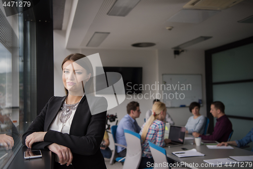 Image of Elegant Woman Using Mobile Phone by window in office building