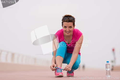 Image of Young woman tying shoelaces on sneakers