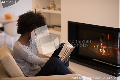 Image of black woman at home reading book