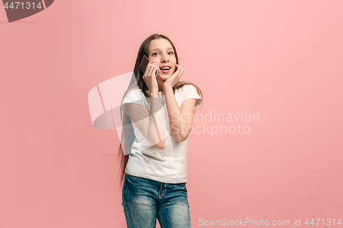 Image of The happy teen girl standing and smiling against pink background.