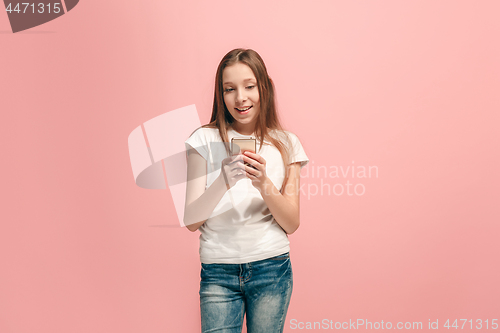 Image of The happy teen girl standing and smiling against pink background.