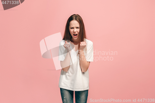 Image of Portrait of angry teen girl on a pink studio background