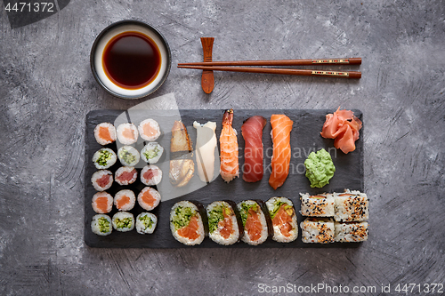 Image of Composition of different kinds of sushi rolls placed on black stone board