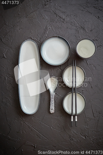 Image of Set of empty ceramic dishes for sushi and rolls on a black stone table